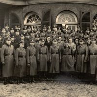 Männer stehen in einer Gruppe.
Sie tragen Uniformen.
Sie blicken ernst in die Kamera.