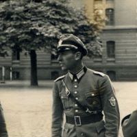 Drei Männer stehen auf einer Straße.
Sie tragen Uniform.