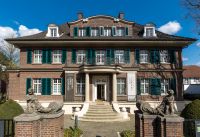 Ein altes Haus mit Backsteinen und grünen Fensterläden.