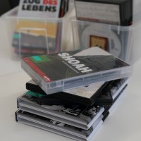 Auf einem Tisch stehen in zwei Schubern und übereinander gestapelt DVDs, obenauf 'Shoah' von Claude Lanzmann.