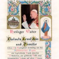 Abgebildet ist eine Urkunde, auf dem neben Verzierungen auch das Foto von Papst Johannes Paul II. zu sehen ist. Der Text besagt: "Eheleute Ernst Bein und Familie bitten Ew. Heiligkeit demütig um den Apostolischen Segen als begleitende Gnade durchs Erdenleben, als göttliche Hilfe und himmlischen Schutz auf allen Wegen." Darunter steht unter anderem in eher unbeholfener Federführung eine Unterschrift "Johannes Paulus PII"