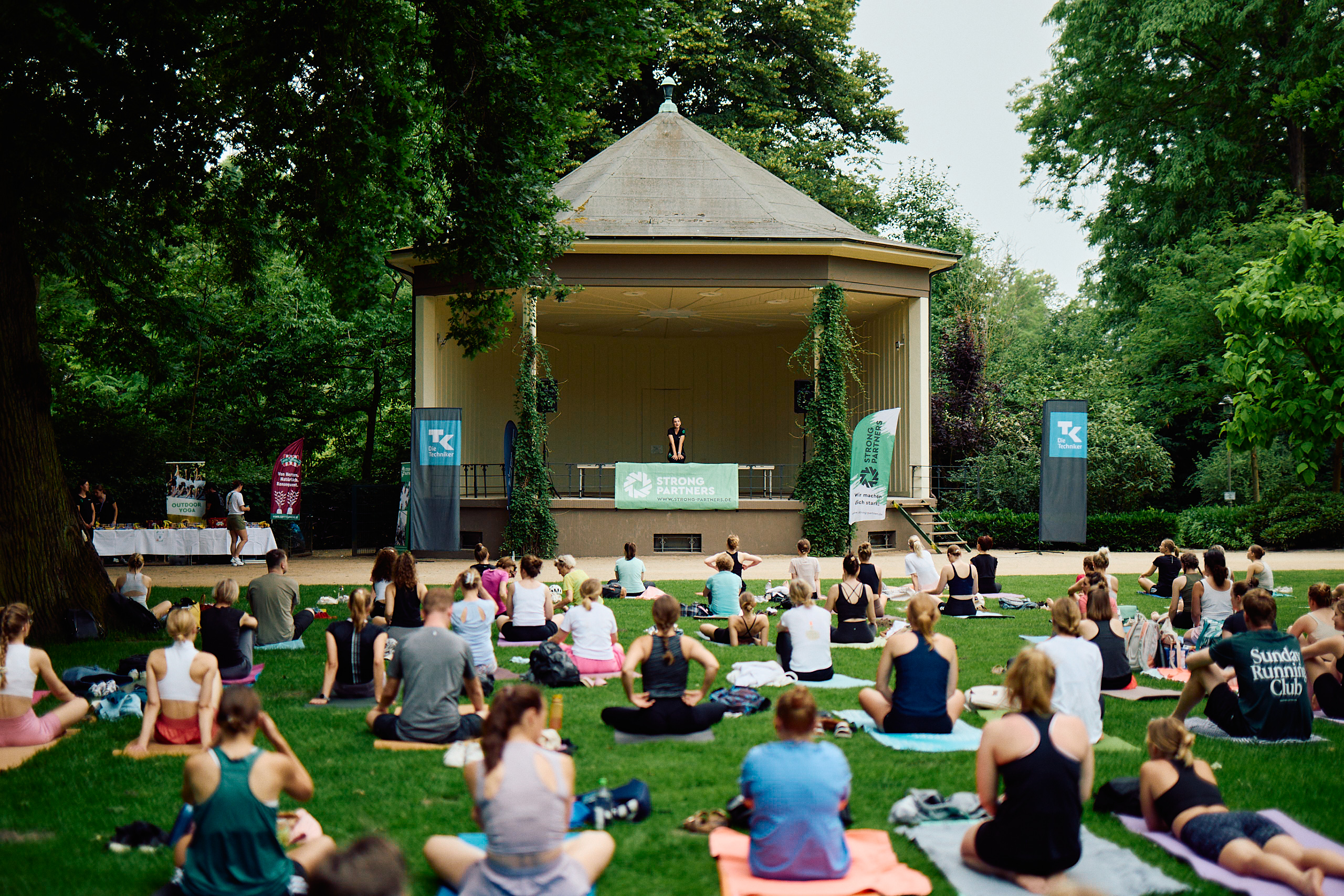 Ein Foto von einer Gruppe Menschen, die auf einer Wiese auf Yogamatten sitzen