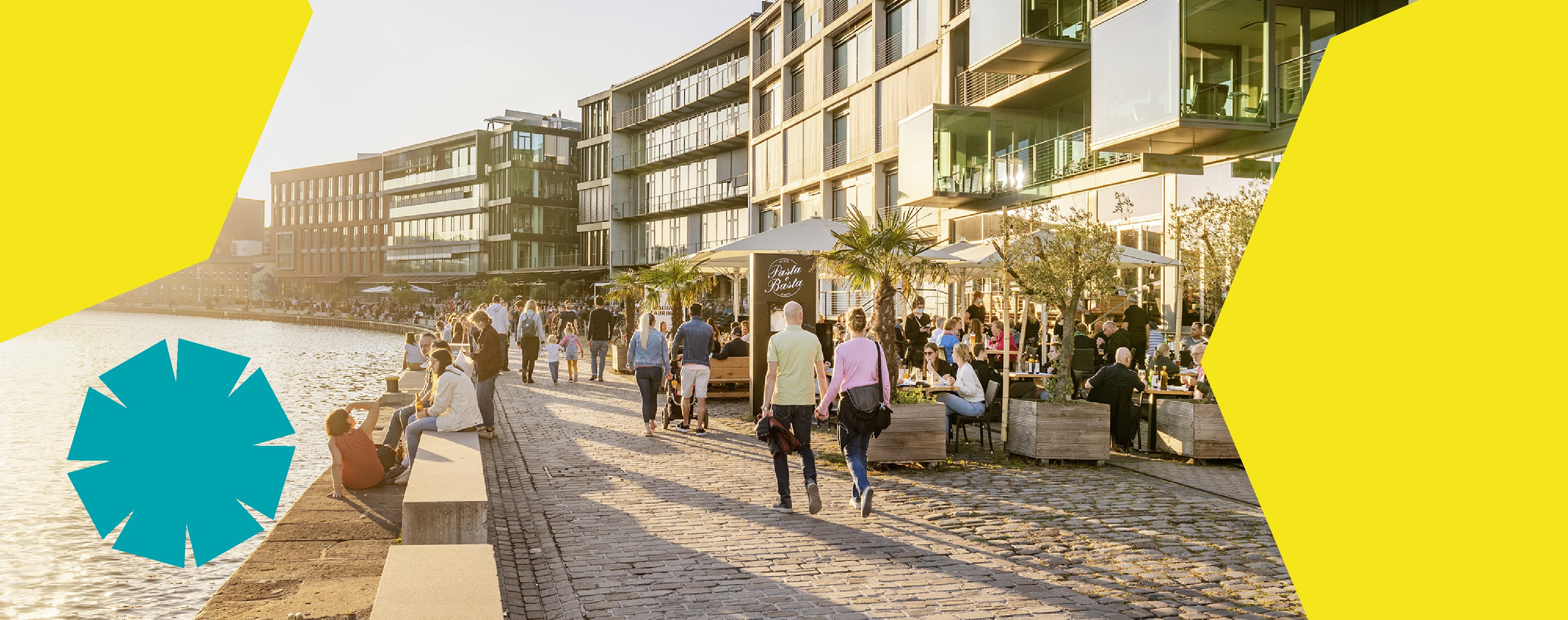 Personen flanieren am Hafen bei tief stehender Sonne