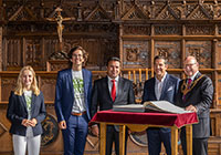 Fünf Personen im Friedenssaal; vor ihnen liegt das Goldene Buch der Stadt Münster
