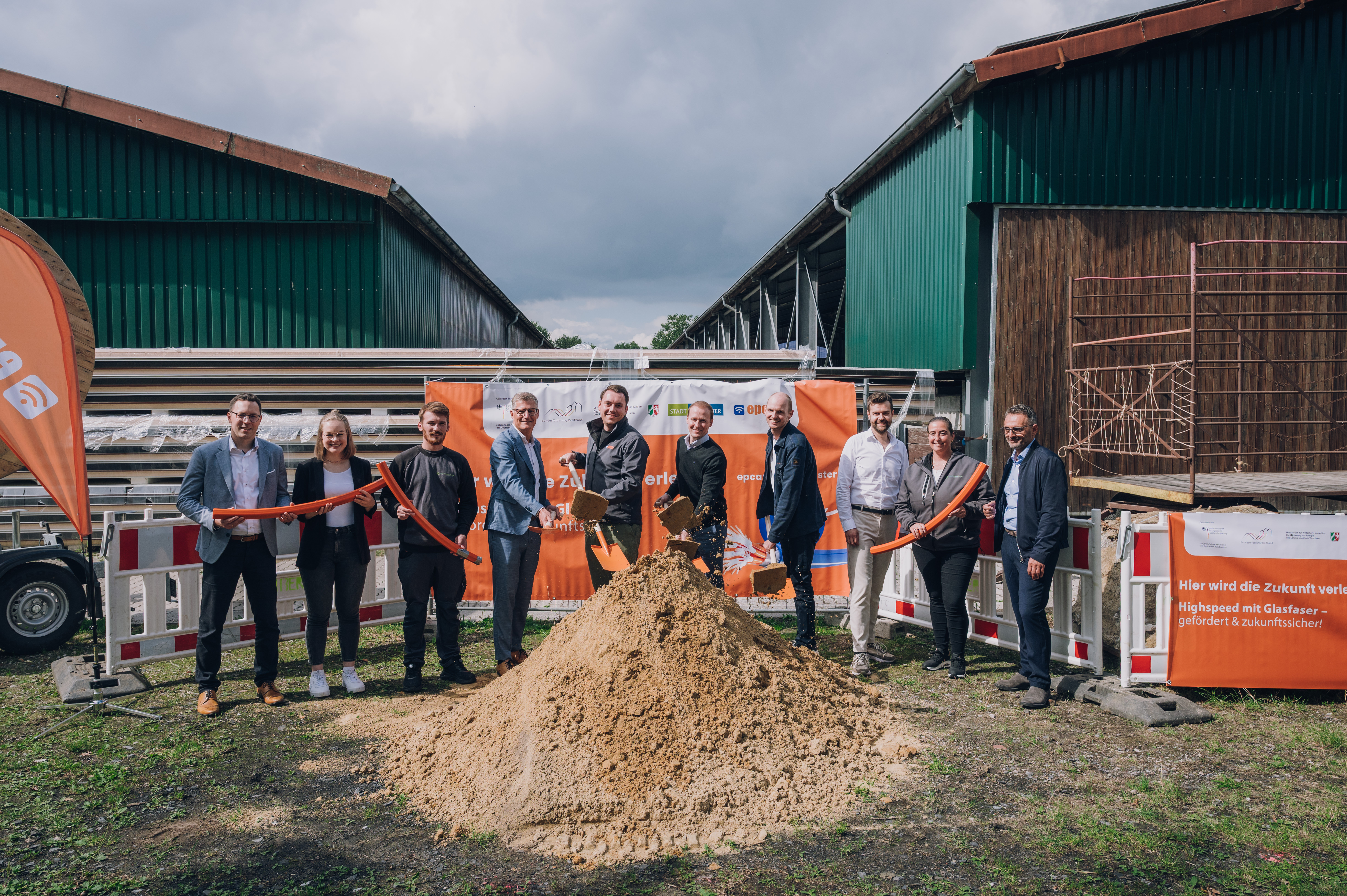 Gruppenbild vom symbolischen Spatenstich mit Schaufeln und einem Sandhaufen