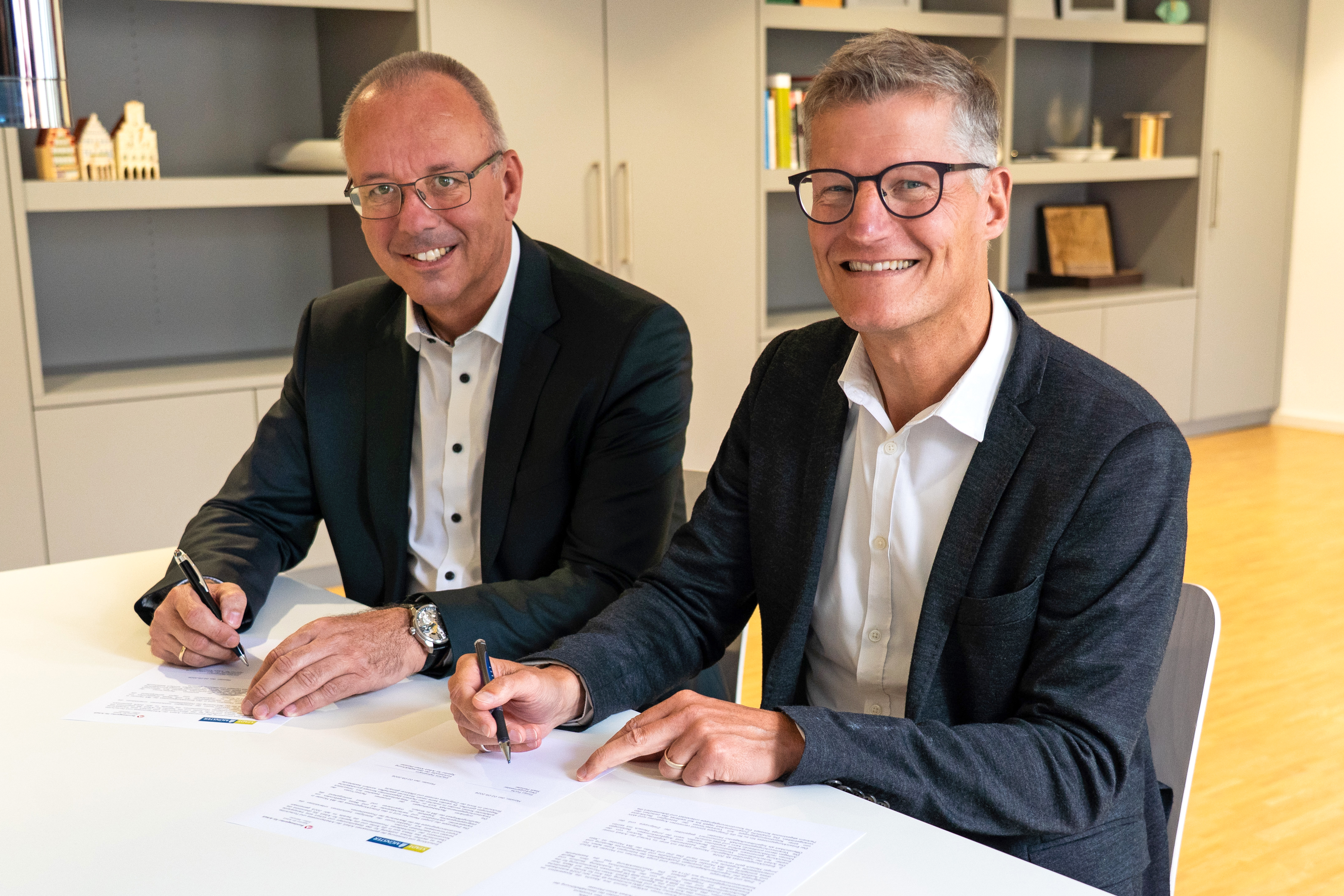 Joachim Fahnemann und Tilman Fuchs unterzeichnen am Schreibtisch die Vereinbarung