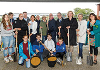 1. Spatenstich für den Neubau der Mathilde-Anneke-Gesamtschule am 12. Juni 2019 Gruppenfoto: Viele Personen mit Spaten in der hand unter einem Dach