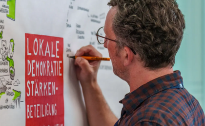 Mann schreibt auf ein Plakat