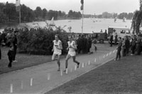 Beim traditionellen Staffellauf "Rund um Münster" zeigt sich die Stärke der Leichtathletikabteilung von Preußen Münster. Hier laufen Harald Norpoth (rechts) und Wolf-Jochen Schulte-Hillen um die Plätze, Bildnachweis: Stadtmuseum Münster, Sammlung Hänschei Zwei Läufer in SC Preußen Münster-Trikots laufen in der Nähe des Aasee über einen für den Wettkampf abgesperrten Weg